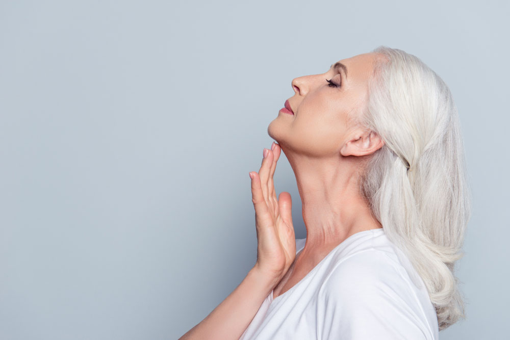 Woman looking up with eyes closed, touching her chin